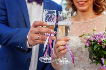 Hands of bride and groom clink glasses with champagne