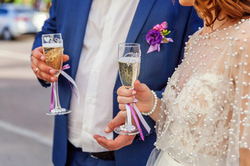 Hands of bride and groom clink glasses with champagne