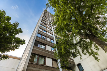 High multistoried apartment building with trees against blue sky. © bilanol