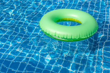 Fototapeta na wymiar Green pool float, ring floating in a refreshing blue swimming pool