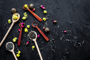 Fototapeta na wymiar Aromatic tea. Wooden spoons with dried tea leaves, flowers and spices on black background top view copyspace