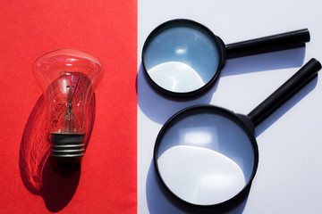 a bulb and magnifying glasses in divided red and white