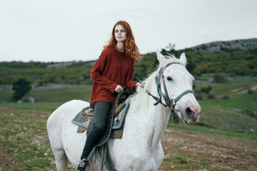 Fototapeta premium Beautiful young woman on nature walks with horse, mountains