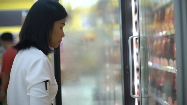Girl taking pack of sausages out from fridge in hypermarket 4k UHD (3840x2160)
