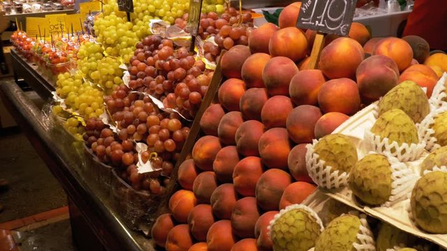 Large Counter with Fruits at a Market in La Boqueria. Barcelona. Spain. Peach, grapes, kiwi, mango and other exotic fruits on display on the showcase at Mercat de Sant Josep.