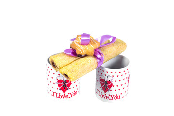 Two cups of coffee with a declaration of love and cookies tied with ribbon on a white background.