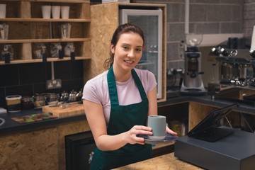 Beautiful waitress holding coffee cup in café
