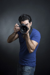 Fototapeta premium fotografo con maglia blu e reflex al collo, scatta una fotografia - sfondo nero