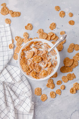 dry breakfast in white plates with milk on a gray background with a towel in a strip, vertically