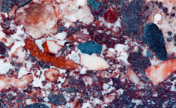 Red marble mineral stone texture pattern macro view. Beautiful ornamental metamorphic rock composed of recrystallized carbonate minerals calcite dolomite. Multicolor gem background