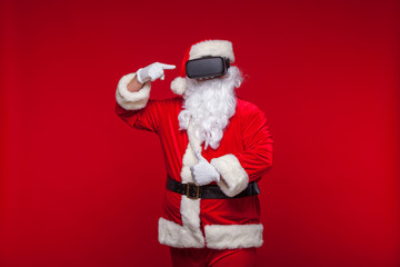 Santa Claus wearing virtual reality goggles, on a red background. Christmas