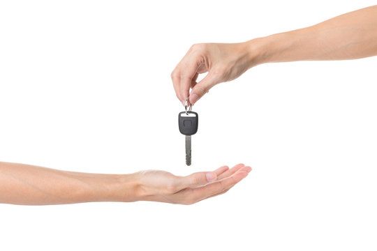 Hand holding car key and handing it over to another person isolated on white background