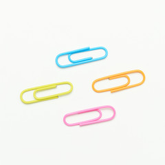 Colored paper clips on white background, with copy space.