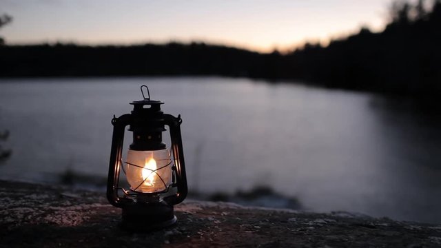 ight from a kerosene lamp on the rocks with a view of the lake