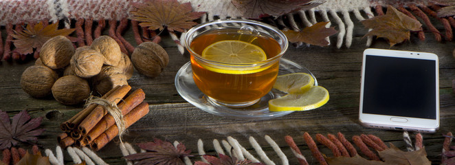 A cup of tea and a mobile phone on a vintage wood background.