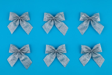 Christmas  bows decoration on bright blue background. Flat lay. Holiday concept. Minimal idea