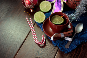 Christmas tea on wooden table with lime and candy canes.