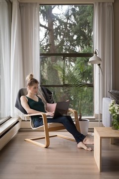 Full length of woman using laptop while sitting on chair