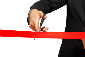 Scissors are cutting red ribbon or tape. Isolated on white background.