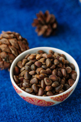 Fresh and ripe pine or cedar nuts in a bowl over blue background.