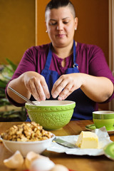 Close up photo of young beautiful adult woman with short hair, sitting behind a kitchen table, sifting the flour into the bowl, home baking concept