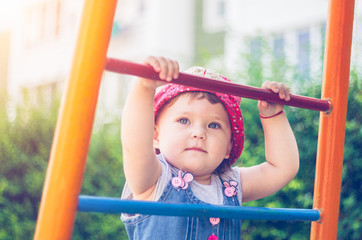Fototapeta premium Little girl scrambles up the stairs in the playground