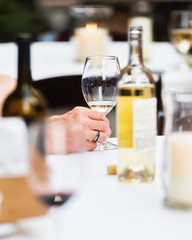 Closeup of a man's hand holding a wine glass at a table