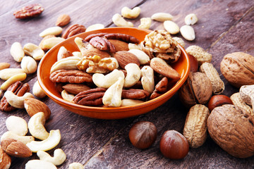 bowl with mixed nuts on wooden background. Healthy food and snack. Walnut, pecan, almonds, hazelnuts and cashews