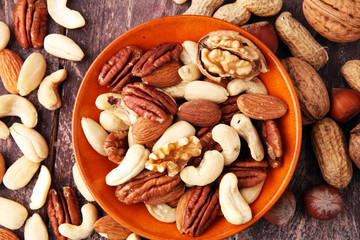 bowl with mixed nuts on wooden background. Healthy food and snack. Walnut, pecan, almonds, hazelnuts and cashews