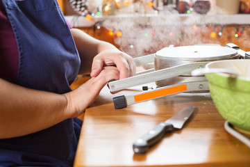 Traditional slovakian christmas wafer making machine. Female hands pressing the handles of the machine together. There is a steam coming out of the machine. Indoors christmas baking concept.