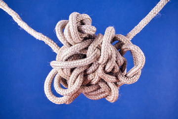 A tangled knot on a rope on a blue background.