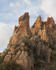 Fototapeta premium Sandstone towers on Eagle's Crag mountain with the formation known as Mrs. Butterworth in front of the others in Southern Utah with white clouds drifting past
