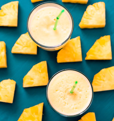 Pineapple smoothie with fresh pineapple on wooden blue table.