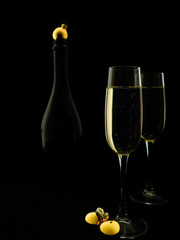 Two glasses and champagne bottle on a black background in New Year's style.