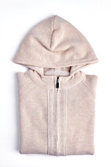 Beautiful beige hooded knitted cardigan. New cotton knit sweater for girls folded on white background. High quality knit outfit on sale.