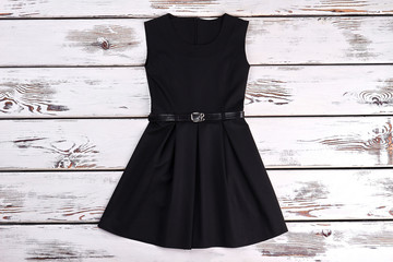 Black sleeveles short cotton dress. A-line black cotton girls dress on old wooden background. Girls...