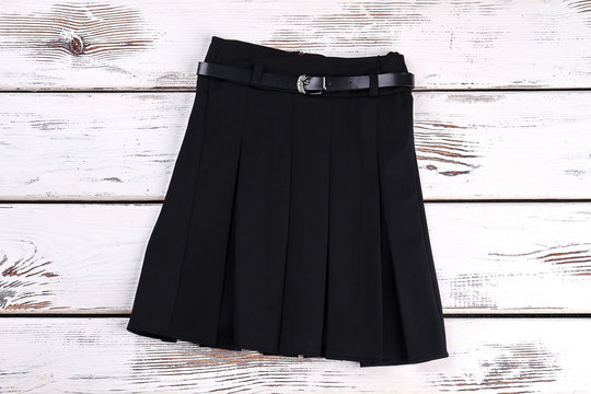 Pleated Black Uniform Skirt. Black Cotton Belted Skirt With Pleats On White Wooden Background. Girls New School Skirt.