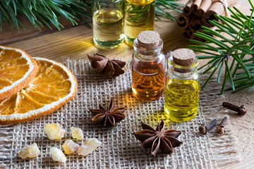 Selection of essential oils with star anise, cinnamon, frankincense, clove, pine and fir branches