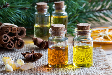 Selection of essential oils with star anise, cinnamon, frankincense and pine branches