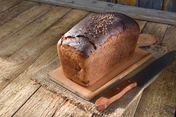 Fresh black bread with coriander seeds on a wooden rustic background. Copy space for your text.