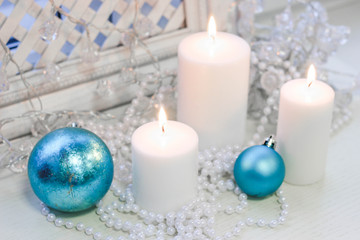 Fototapeta na wymiar White christmas candles and blue balls on a white wooden background