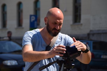 urban bald bearded cameraman working outdoors on a sunny day