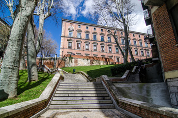 Stairs in a street of Madrid downtown and a red building at the end