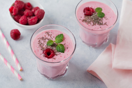 Raspberry smoothie with chia seeds and mint in a glass cup on a gray light stone or concrete background. Healthy and tasty breakfast. Selective focus.