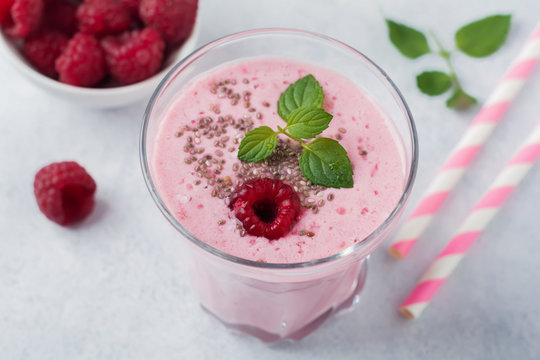 Raspberry smoothie with chia seeds and mint in a glass cup on a gray light stone or concrete background. Healthy and tasty breakfast. Selective focus.