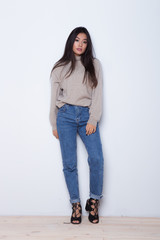 Fashion posing beautiful Asian girl in trendy wearing. Casual wearing in jeans, high heel shoes and sweeter