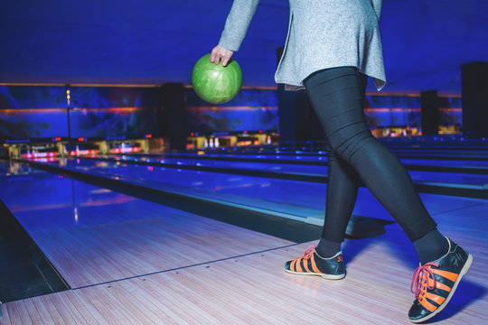 A woman in black clothes plays a bowling red with a bright layer. Active leisure for a bowling game