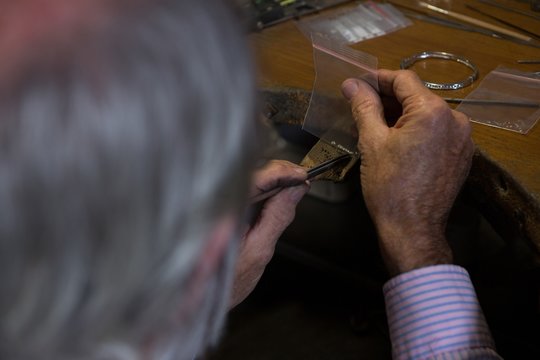 Goldsmith working at desk in workshop