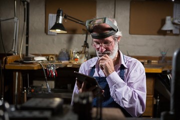 Goldsmith using digital tablet in workshop