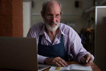 Goldsmith writing in book at workshop